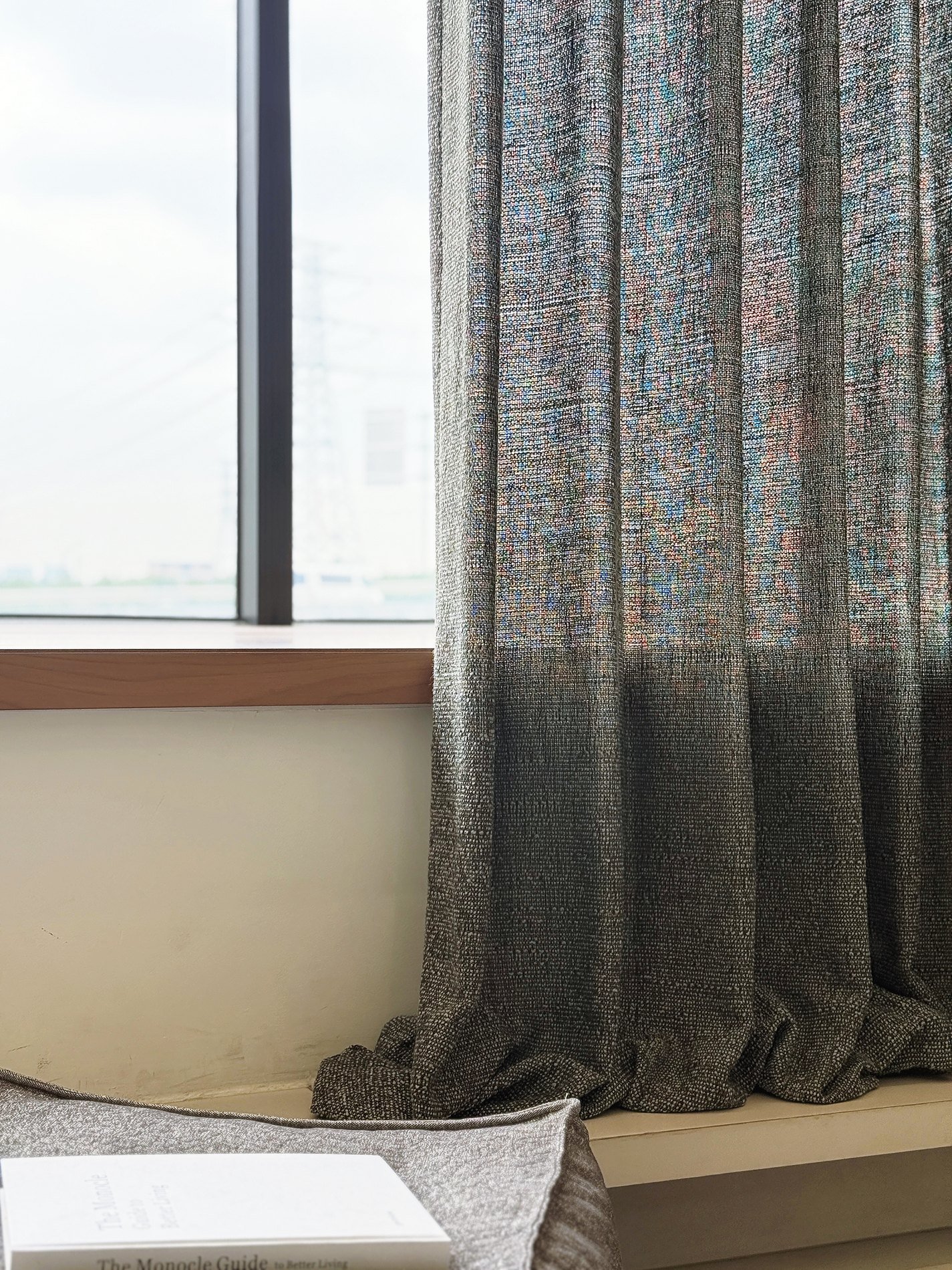 Grey drapery fabric pooling by a window in natural light