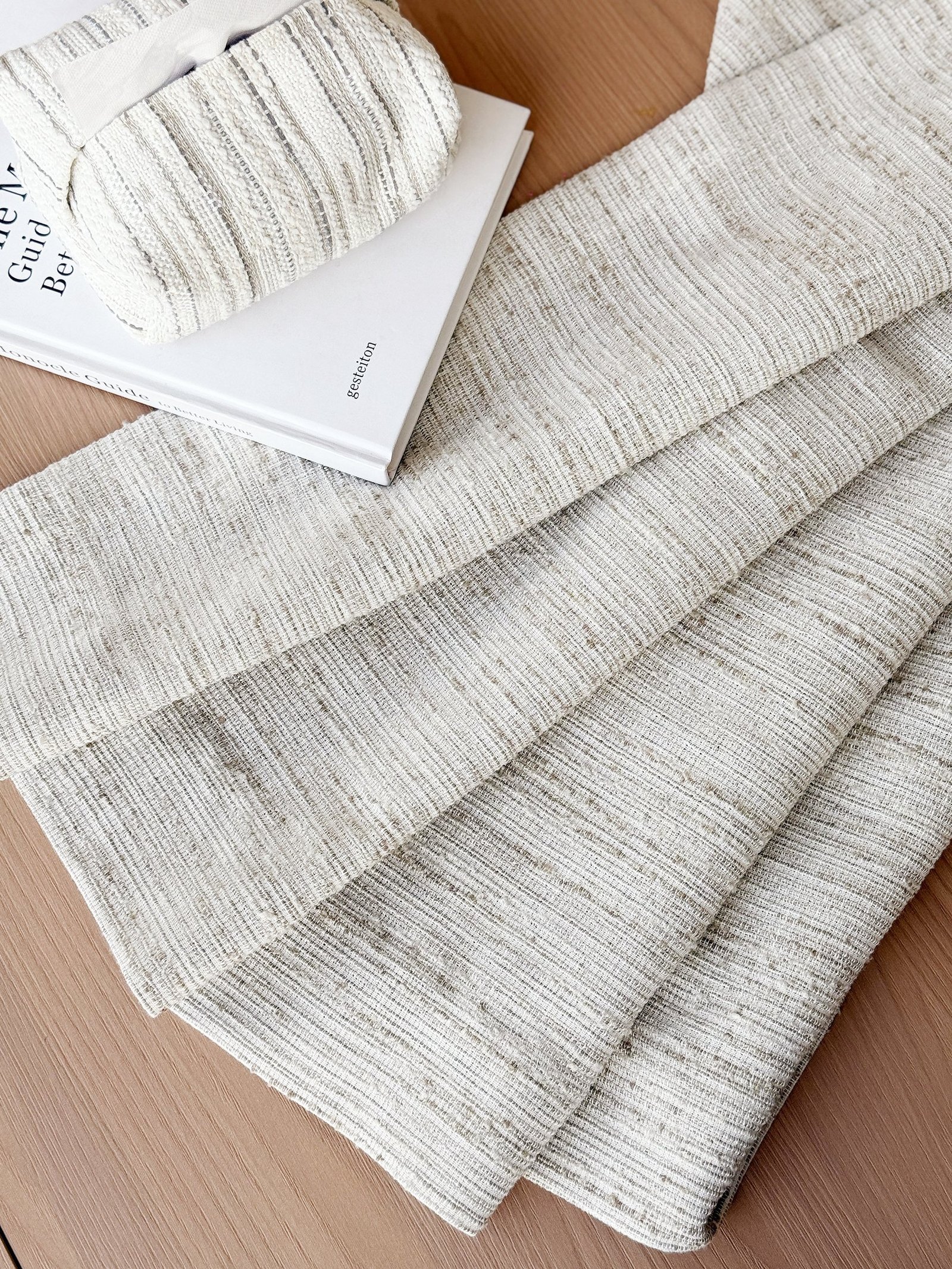 Layered neutral fabric swatches with woven textures and sheer material