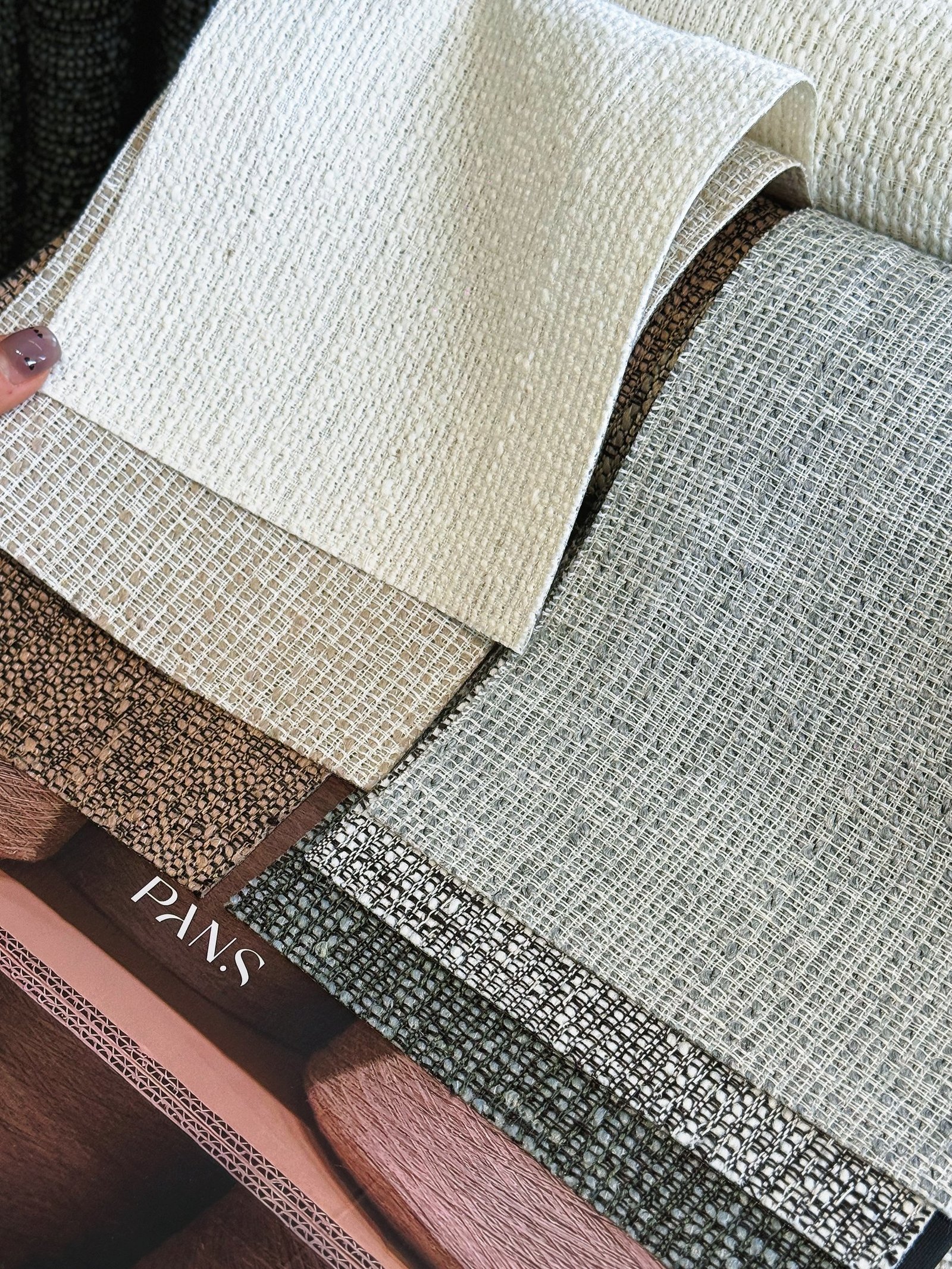 Layered upholstery fabric swatches in neutral woven textures